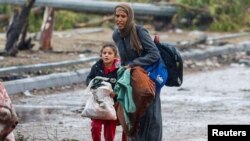 Một phụ nữ Palestine chân không cùng con gái đi dưới mưa về phía nam trong cuộc ngưng bắn tạm thời giữa Israel và Hamas, gần Thành phố Gaza, ngày 27/11/2023.