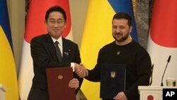 TƯ LIỆU - Thủ tướng Nhật Bản Fumio Kishida (trái) và Tổng thống Ukraine Volodymyr Zelenskyy bắt tay chào nhau sau lễ kí kết các văn kiện chung ở Kyiv, Ukraine, ngày 21 tháng 3 năm 2023.