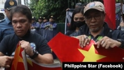 Các thành viên nhóm Makabansa của Philippines xé giấy in hình cờ đỏ sao vàng của Việt Nam khi biểu tình trước cửa Đại sứ quán Việt Nam ở Manilia, Philippines, vào ngày 1/8/2023.