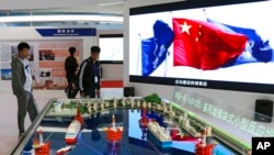 Tư liệu - Du khách xem mô hình lò phản ứng hạt nhân nổi và giàn khoan dầu tại gian hàng trưng bày của Tập đoàn Hạt nhân Quốc gia Trung Quốc thuộc sở hữu nhà nước của Trung Quốc trong Triển lãm Quốc tế Trung Quốc về Công nghiệp Điện Hạt nhân ở Bắc Kinh, ngày 27 tháng 4 năm 2017.