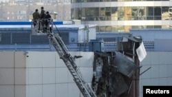 Công nhân và nhân viên cấp cứu đang xem xét mái nhà bị hư hại của một tòa nhà ở Moscow bị máy bay không người lái được cho là của Ukraine đâm vào hôm 18/8. 