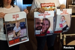 سوئٹزرلینڈز میں یرغمال خاندان کی رہائی کے لیے مظاہرے میں شامل افراد ان کے پوسٹر اٹھائے ہوئے ہیں۔ 13 نومبر 2023