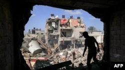 جنوبی غزہ کی پٹی کے علاقے خان یونس میں ایک نوجوان اسرائیلی بمباری کے دوران تباہ ہونے والی عمارت کی دیوار کے سوراخ کے سامنے کھڑا ہے جبکہ دیگر افراد زندہ بچ جانے والوں یا ملبےمیں لاشوں کو تلاش کر رہے ہیں۔