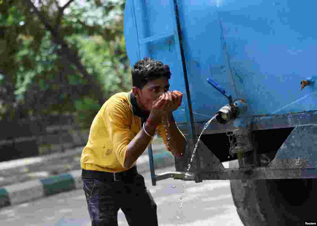 بھارت میں ایک شخص گرمی میں پیاس کی شدت کم کرنے کے لیے ٹینکر سے پانی پیتے ہوئے۔