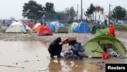 Những người di cư cố gắng chuẩn bị một bữa ăn dưới cơn mưa rào tại một trại tạm thời ở biên giới Hy Lạp-Macedonian, gần làng Idomeni, Hy Lạp, ngày 09/3/2016.