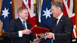Bộ trưởng Quốc phòng Anh Grant Shapps (trái) và Bộ trưởng Quốc phòng Úc Richard Marles trao đổi thỏa thuận hợp tác quốc phòng và an ninh mới tại Canberra, vào ngày 21/3/2024.