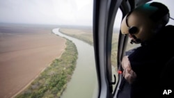 امریکی بارڈر فورس کا ایک اہلکار ہیلی کاپٹر کے ذریعے امریکہ میکسیکو سرحد کا معائنہ کر رہا ہے (فائل فوٹو)