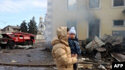 Một người dân địa phương bế con đi ngang qua nhà ga xe lửa bị phá hủy bởi cuộc tấn công tên lửa của Nga ở Kostyantynivka, vùng Donetsk, vào ngày 25/2.