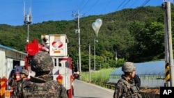Bức ảnh do Trụ sở Cứu hỏa Jeonbuk cung cấp cho thấy những quả khí cầu chứa rác do Triều Tiên gửi đến, mắc trên dây điện khi các binh sĩ quân đội Hàn Quốc đứng gác ở Muju, hôm 29/5.