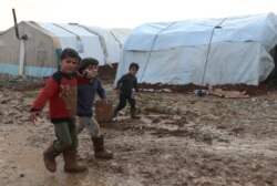 بے گھر افراد کے کیمپ میں کیچڑ میں بھاگتے بچے