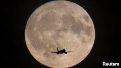 ایک طیارے کے پس منظر میں چوھدویں کا چاند دکھائی دے رہا ہے۔ 