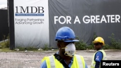 Công nhân xây dựng đứng trước một tấm bảng của 1MDB ở Kuala Lumpur, Malaysia. (Ảnh tư liệu)