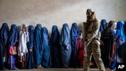 23 مئی، 2023 کو کابل، افغانستان میں، ایک طالبان جنگجو پہرے میں کھڑا ہے جب خواتین انسانی امدادی . گروپ کی طرف سے تقسیم کردہ خوراک کا راشن حاصل کرنے کا انتظار کر رہی ہیں۔ فوٹو اے پی