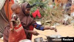 خوراک کی قلت کے شکار صومالیہ میں ایک خاتون اپنے بچے کے ساتھ کھانا پکاتے ہوئے، فائل فوٹو