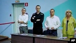 Lãnh đạo phe đối lập Nga Alexei Navalny (thứ 2, bên trái) được nhìn thấy trên màn hình TV đứng giữa các luật sư của mình khi ông xuất hiện trong phiên xử tại trại giam ở Melekhovo, Nga, vào ngày 4/8/2023.