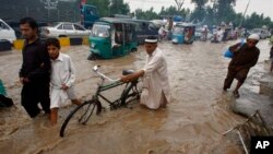 Cư dân lột qua con đường bị ngập lụt vì mưa mùa tại Peshawar, Pakistan, ngày 5/8/2013.