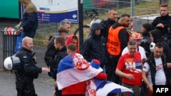 Alman polisi, 16 Haziran'da Gelsenkirchen'de Sırbistan-İngiltere maçı öncesinde Arena AufSchalke'ye gelen taraftarlarla konuşuyor. Gelsenkirchen, Sırp taraftarların Almanya'ya gelen on binlerce İngiliz taraftarla çatışmasından korkulduğu için yüksek riskli ilan edilmişti