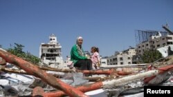 غزہ میں ایک خاتوں عید کے دوسرے روز اپنی بیٹی کے ساتھ مکان کے ملبے پر بیٹھی ہے۔ غزہ میں لاکھوں فلسطینیوں کے پاس کھانے کے لیے کچھ نہیں ہے۔ 11 اپریل 2024
