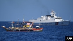 Một tàu bảo vệ bờ biển Trung Quốc đi ngang qua một tàu đánh cá Philippines gần Bãi cạn Scarborough do Trung Quốc kiểm soát, trong khu vực tranh chấp ở Biển Đông hôm 15/2.