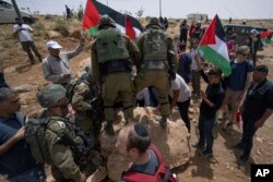 مقبوضہ مغربی کنارے میں فلسطینیوں اور اسرائیلی فوجیوں کے درمیان سڑک کے ایک پتھر کو ہٹانے پر تنازعے کی ایک تصویر ، فوٹو اے پی 13 مئی 2022