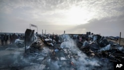 فلسطینی اسرائیلی حملے کے بعد تباہی کو دیکھ رہے ہیں جہاں 27 مئی 2024 کو غزہ کی پٹی کے رفح میں بے گھر لوگ مقیم تھے۔